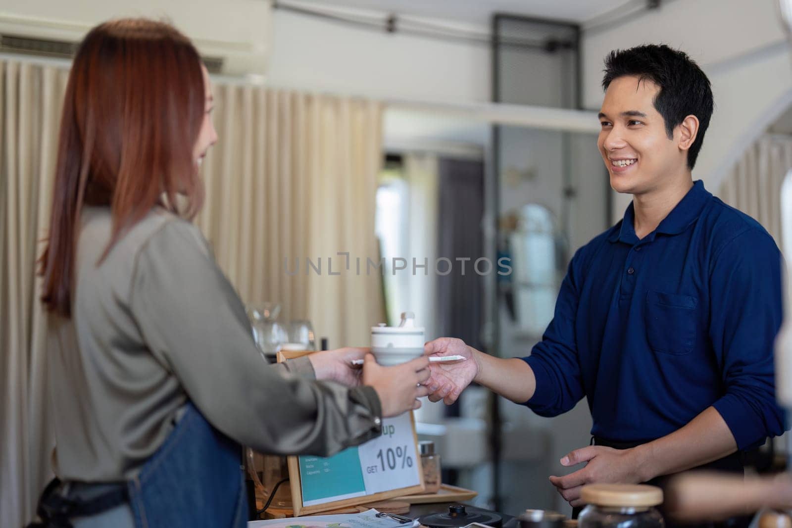 A cheerful barista serves a beverage to a customer, highlighting the importance of sustainable practices through ecologically conscious choices.