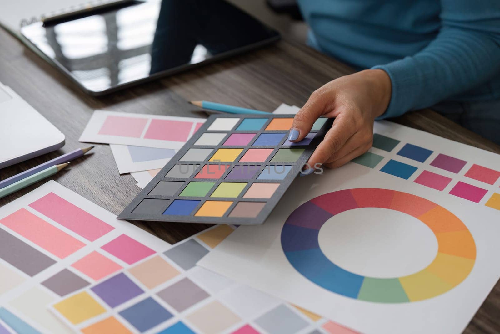 A designer evaluates a color palette, reviewing swatches and color wheels to finalize design choices, showcasing creativity and attention to detail.