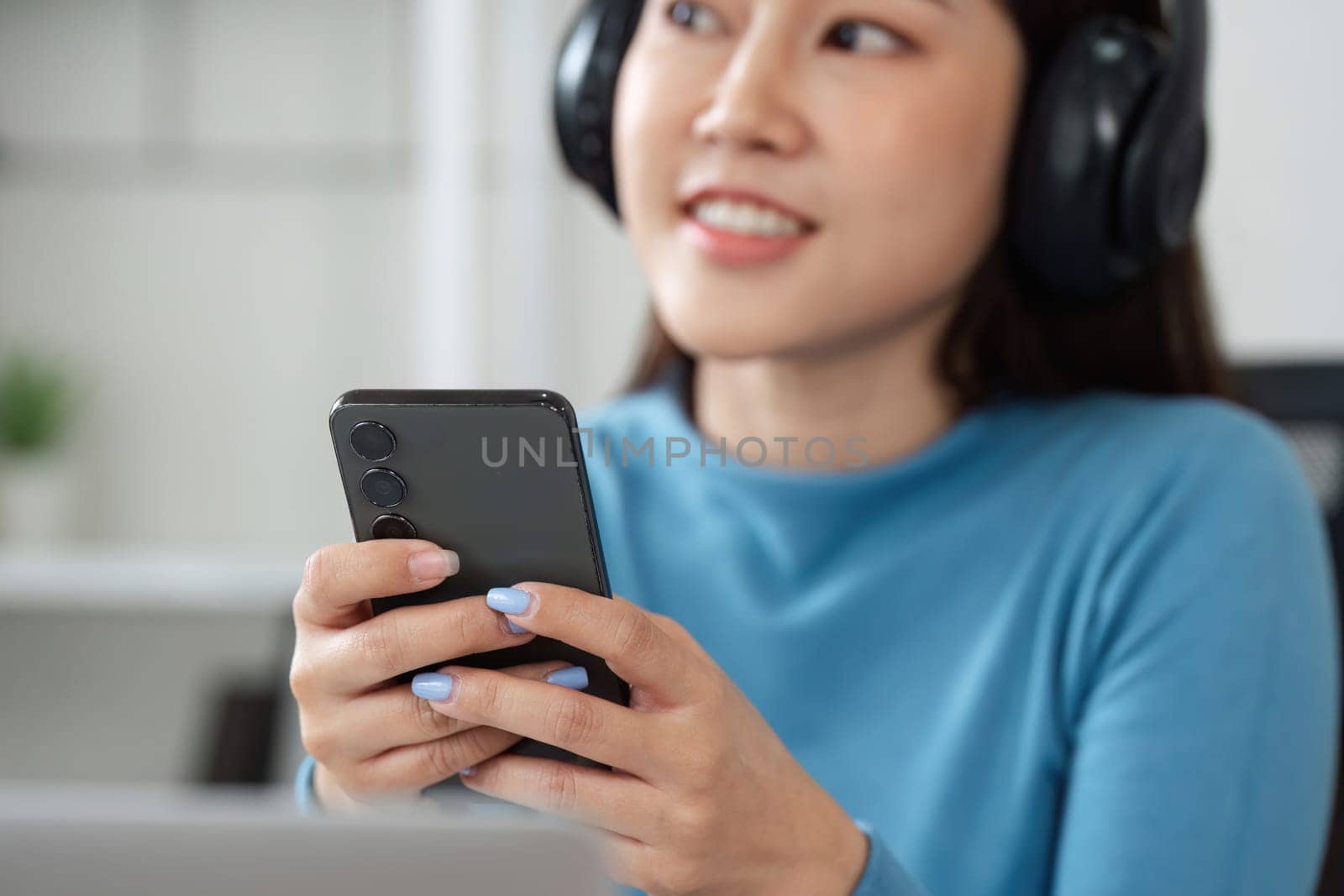 A content woman listens to music with headphones and engages with her smartphone, highlighting the merging of technology and personal leisure.