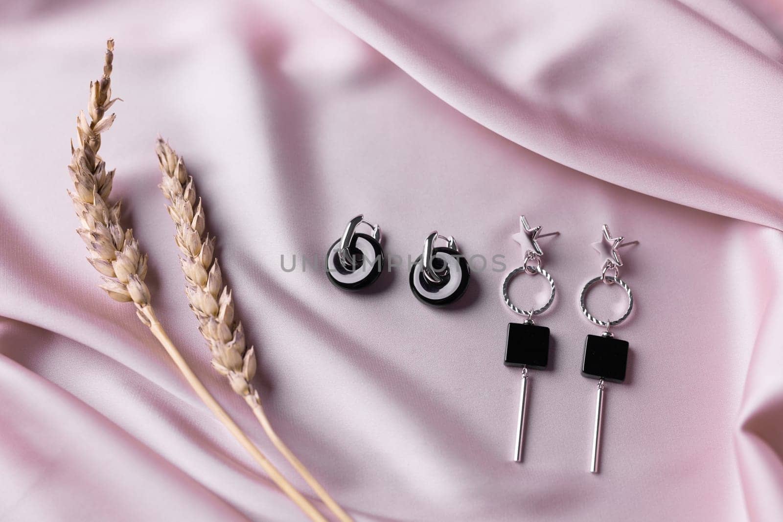 Female Jewelry. Vintage bijouterie jewelry. Beautiful handmade silver earrings on pink silk background. Flat lay, top view copy space and empty space for text.