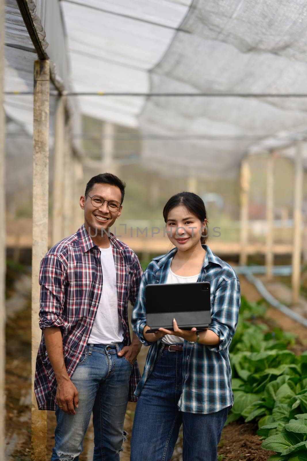 Confident farmers with digital tablet standing in organic farm. Smart farming concept.
