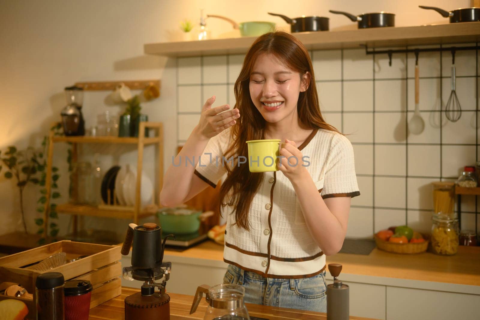 Young woman savoring the aroma of freshly brewed coffee in a cozy kitchen.