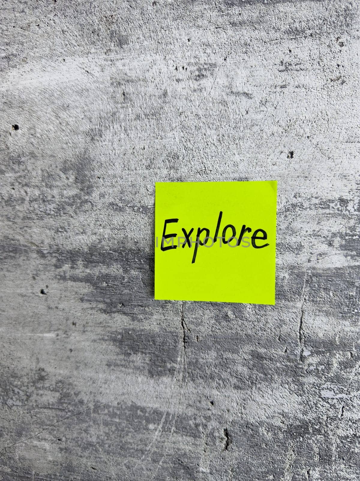 Bright yellow sticky note with the word Explore prominently displayed on a textured grey background, signifying the spirit of adventure and the pursuit of new experiences