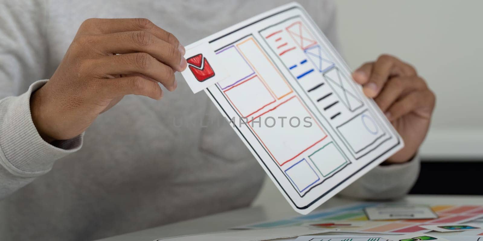 A designer meticulously organizes and evaluates digital prototypes, showcasing the importance of hands-on UX UI design in refining applications.