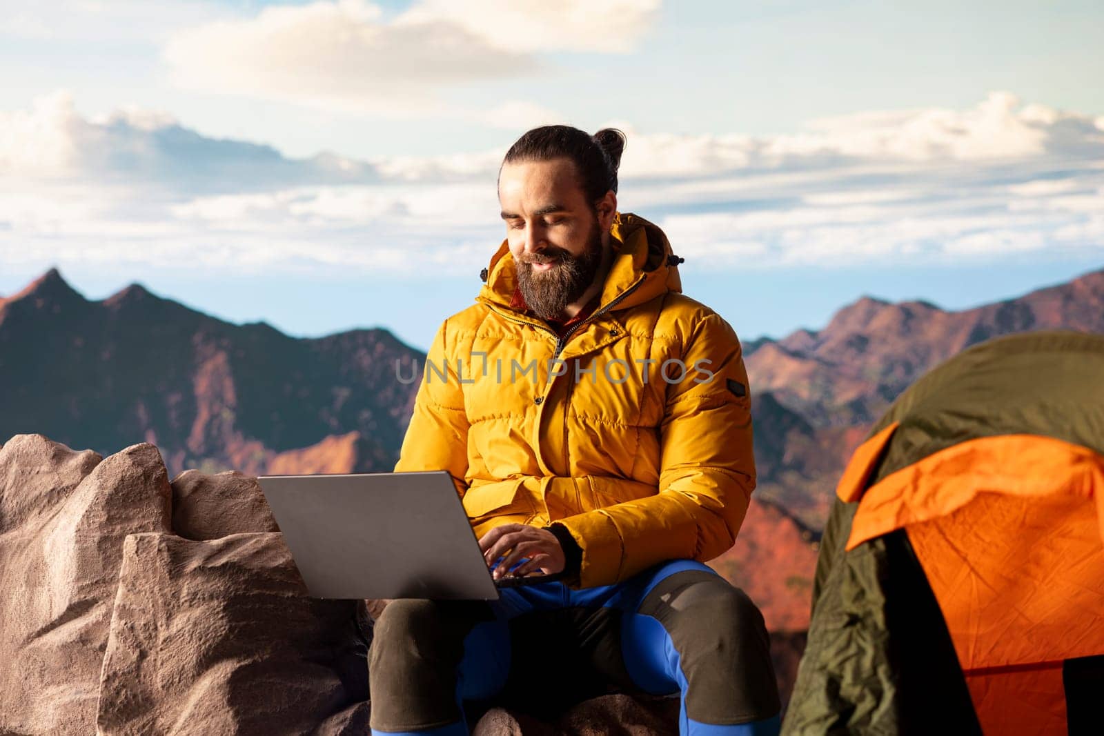 Young explorer keeps working at the top of the mountain with internet everywhere, enjoying global connectivity and productivity on the hill summit. High speed strong signal on a hike.