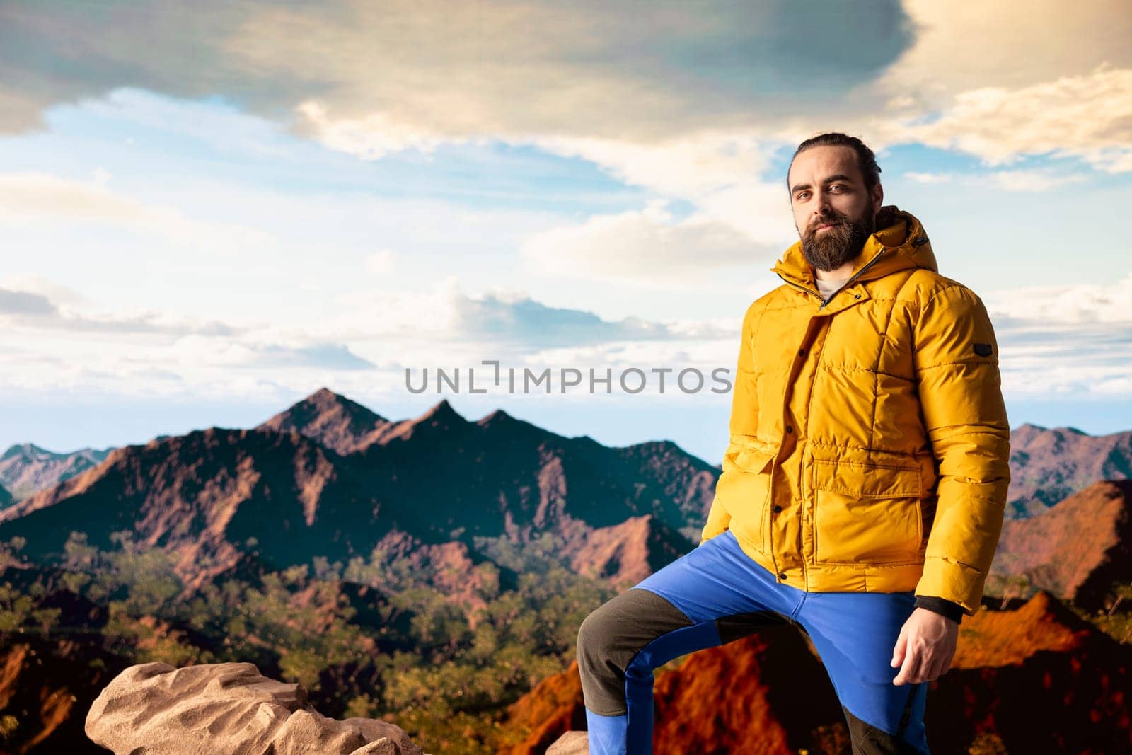 Portrait of explorer alone at the edge of a towering mountain range, gazing at the clouds and stunning panoramic scenery. Pleased hiker showcasing personal growth and perseverance.