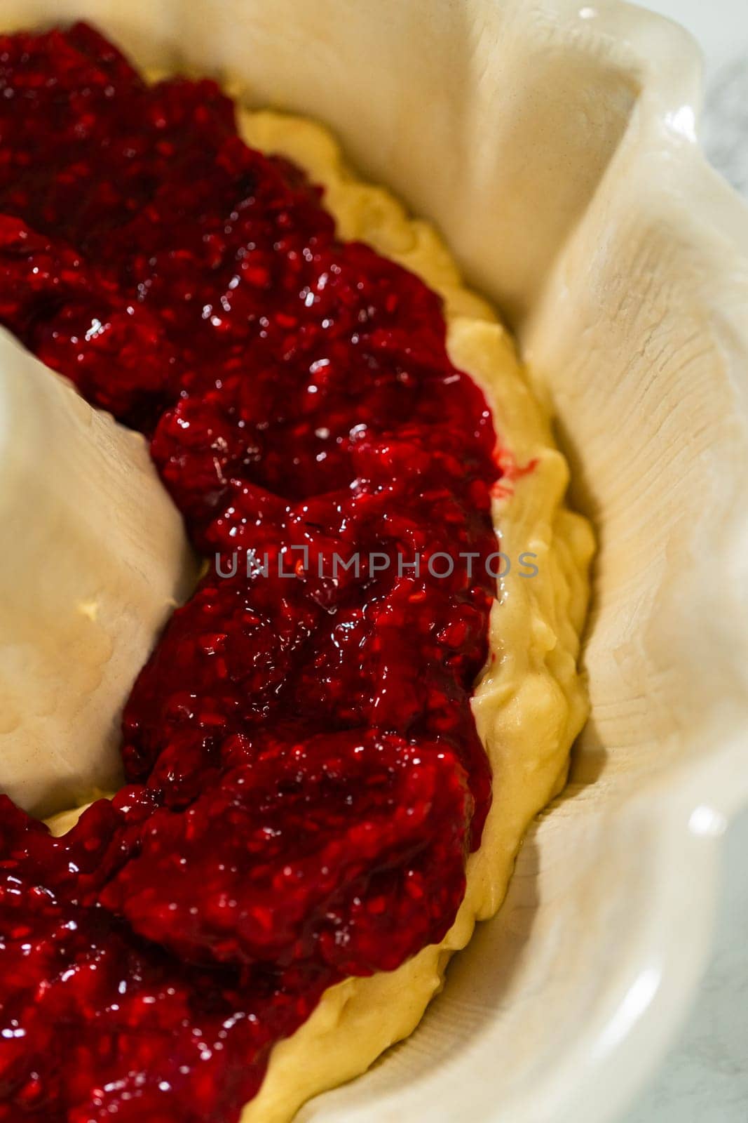 After greasing the bundt cake pan, it's time to fill it with the prepared cake batter and delightful raspberry cake filling - creating a perfect harmony of flavors.