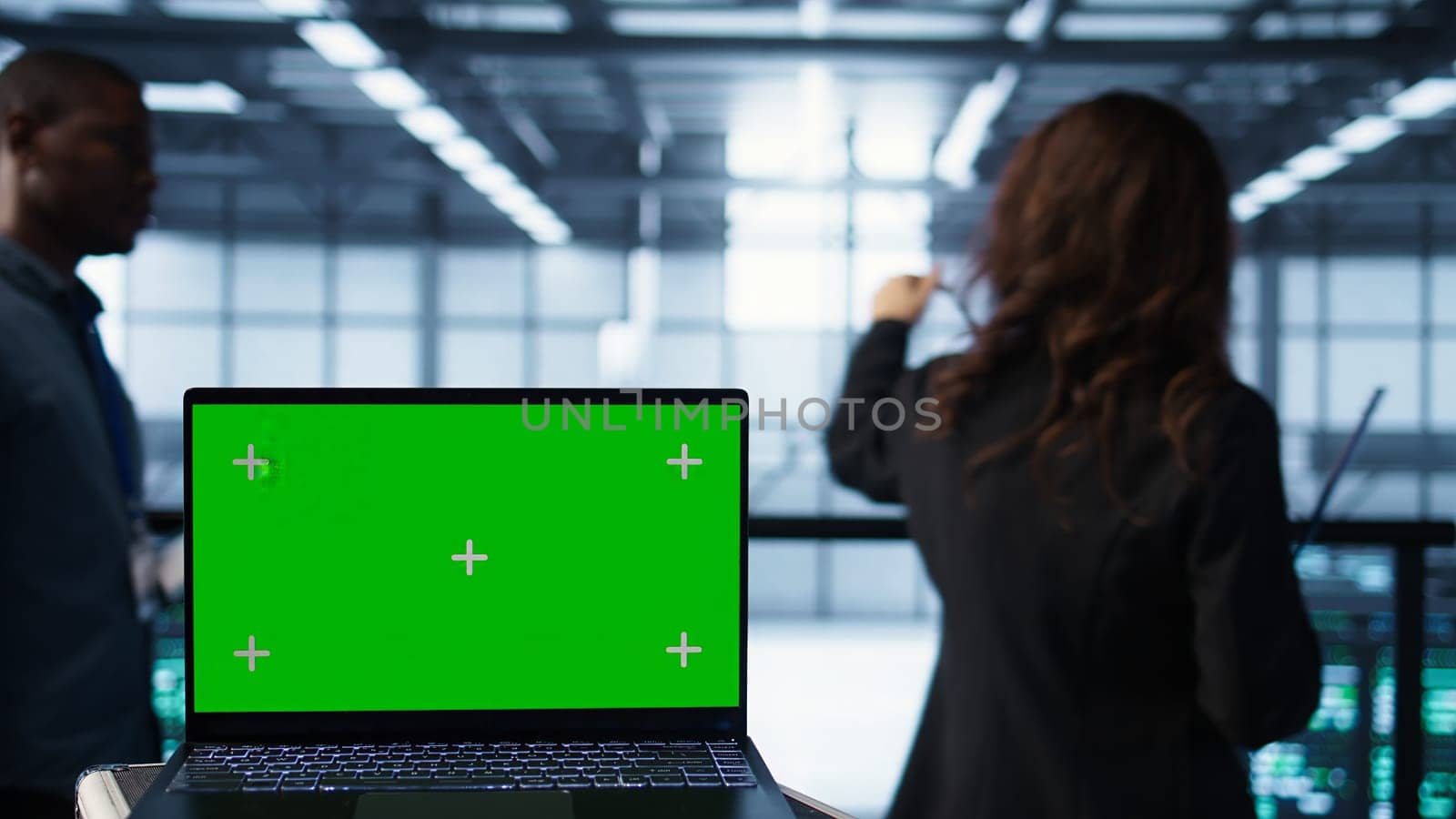 Mockup laptop in front of software developers walking in data center, reviewing equipment diagnostics. Close up of isolated screen notebook next to teamworking IT professionals in server farm