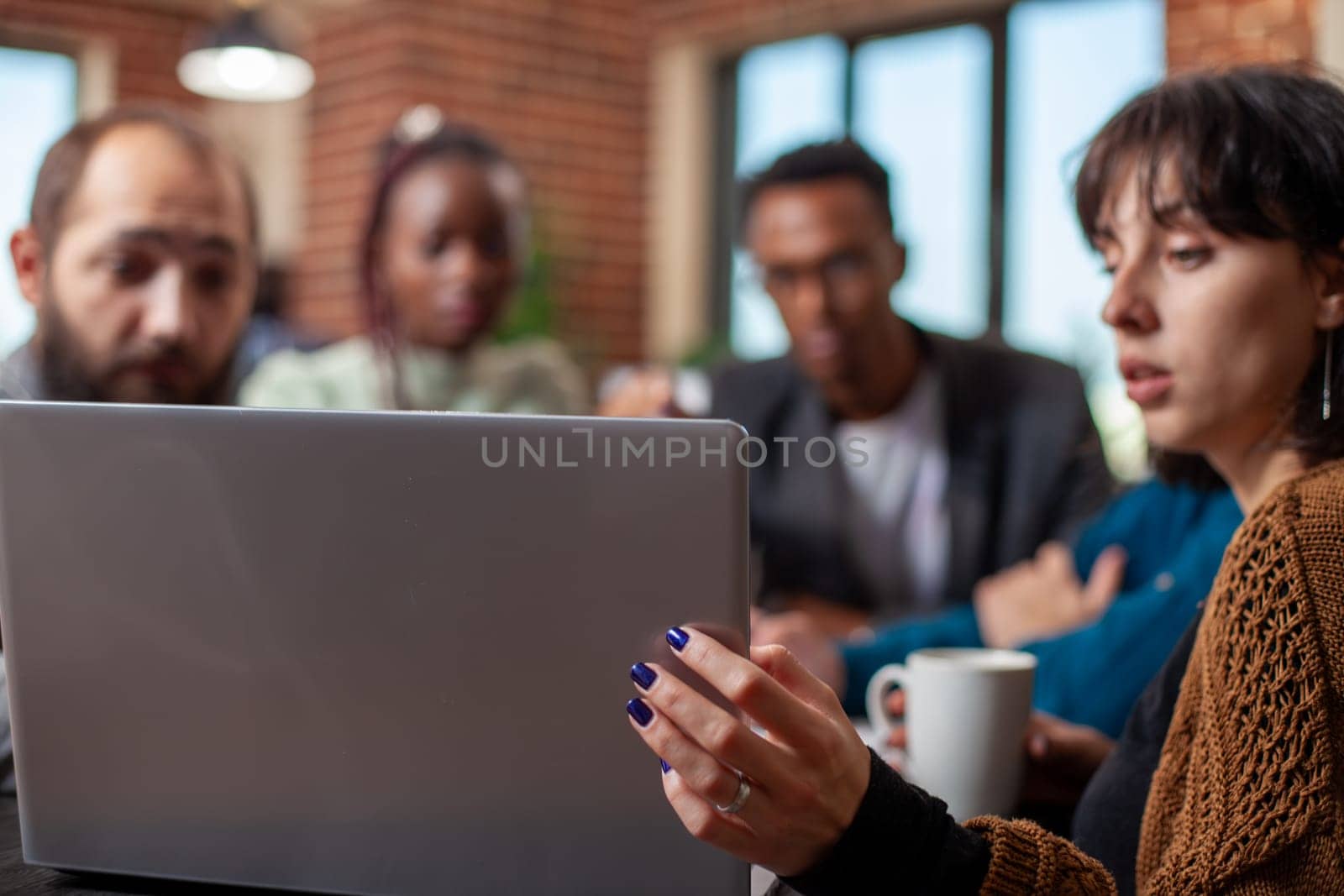 Closeup of a collaborative discussion among diverse colleagues, looking at online documents on device. Startup team engaged in discussing strategies during a project meeting with a laptop in focus.