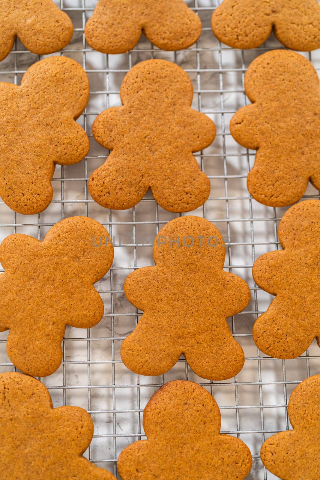 Close-up of golden-brown gingerbread men with heart-shaped cutouts cooling on a wire rack.