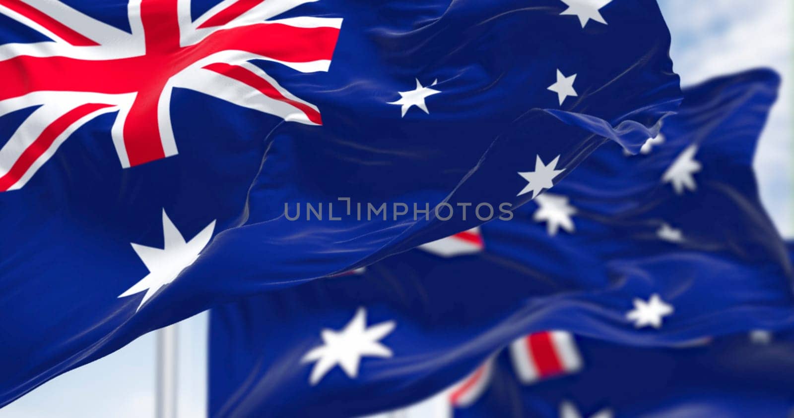 Australia national flags waving in the wind on a clear day. Blue flag with Union Jack, white 5-pointed star symbolizing Southern Cross. 3d illustration render. Rippled fabric. Selective focus