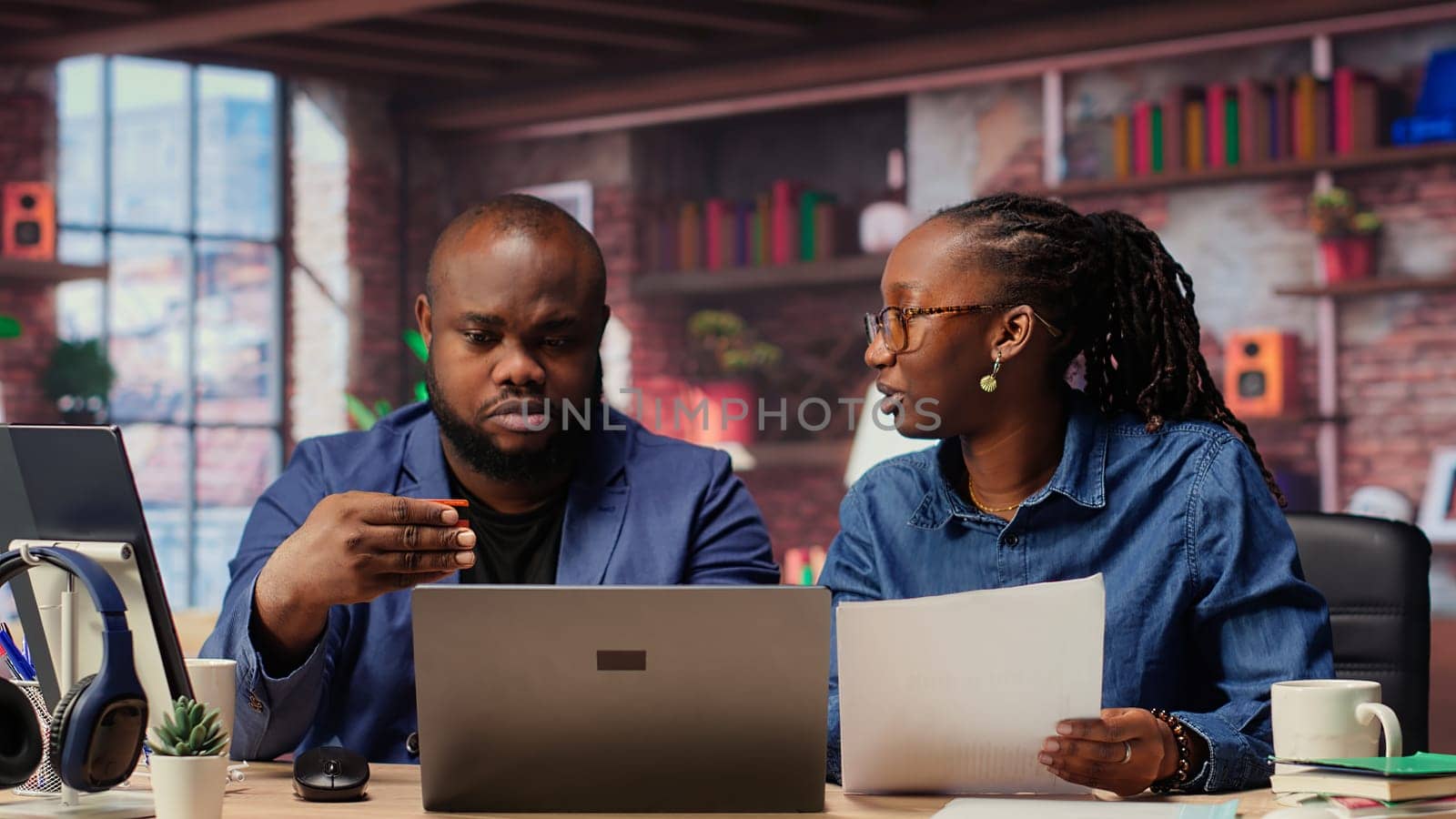 African american people at home entering card digits to renew an account subscription, managing streaming services on laptop. Couple transferring money, updating the credentials. Camera B.