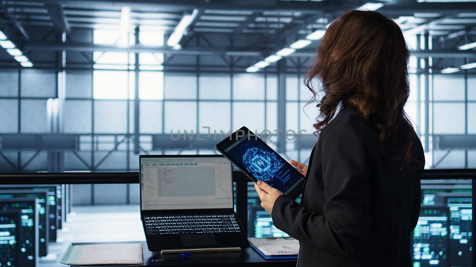 Technician in data center with tablet integrating AI driven automation tools, running predictive maintenance routines. Woman ensuring continuous uptime of server room, managing data flows, camera B