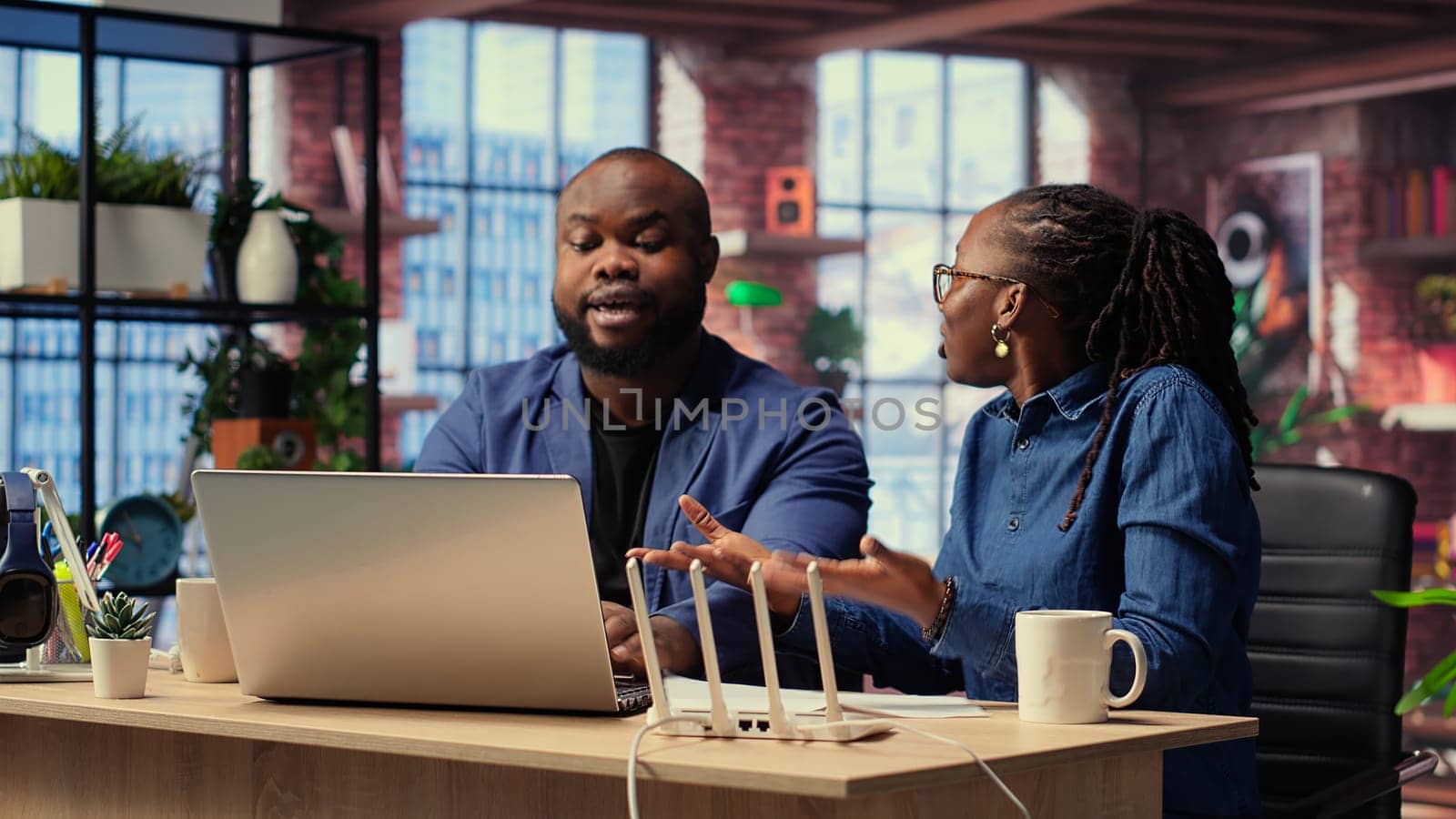 Angry African American people tries to reset the Wi Fi modem due to signal loss, woman arguing and being irritated. Frustrated couple fighting over troubleshooting methods. Camera B.