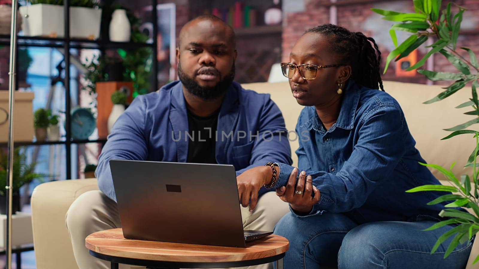 African american couple work on a management project for freelancing, using a laptop to research business trends and manage an online brand. Successful remote career development. Camera B.