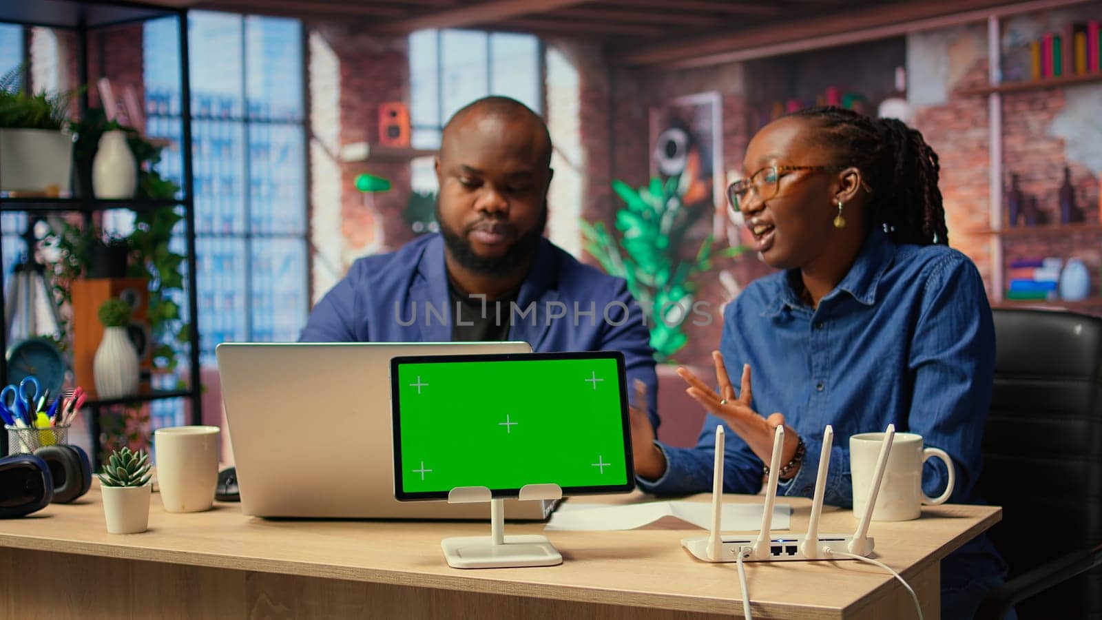African American couple browse troubleshooting guide next to chroma key, working together to debug router issues and restore their home network. Freelancers getting angry. Camera A.