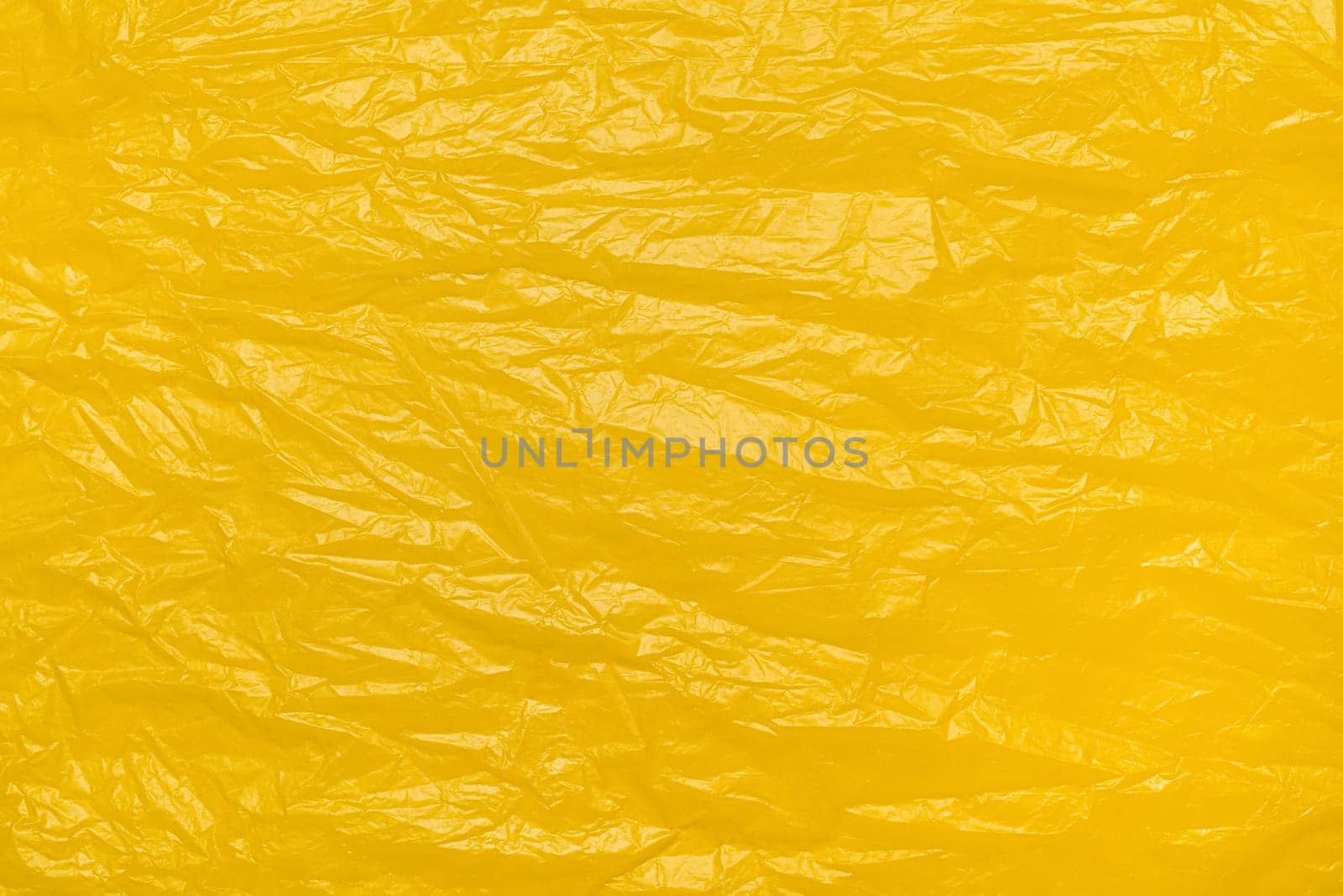 A textured yellow crumpled paper background with natural creases and folds. Ideal for design projects, digital graphics, or creative presentations requiring a vibrant.