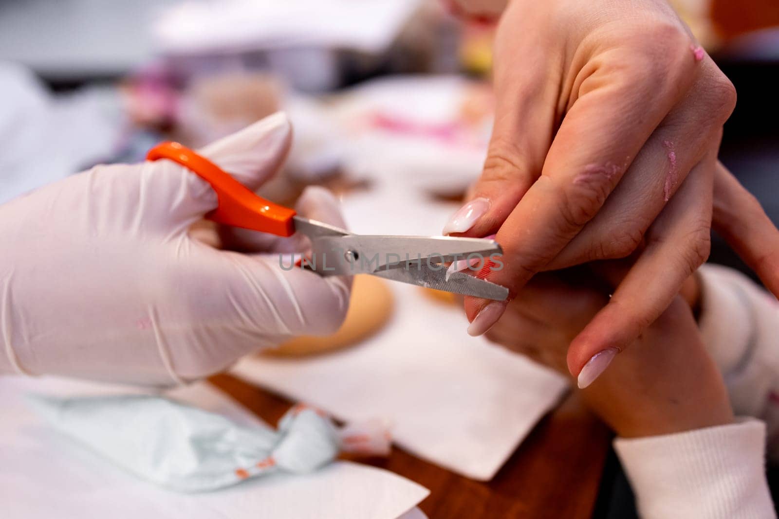 Female manicure process with hands clipping nails close up in salon setting.