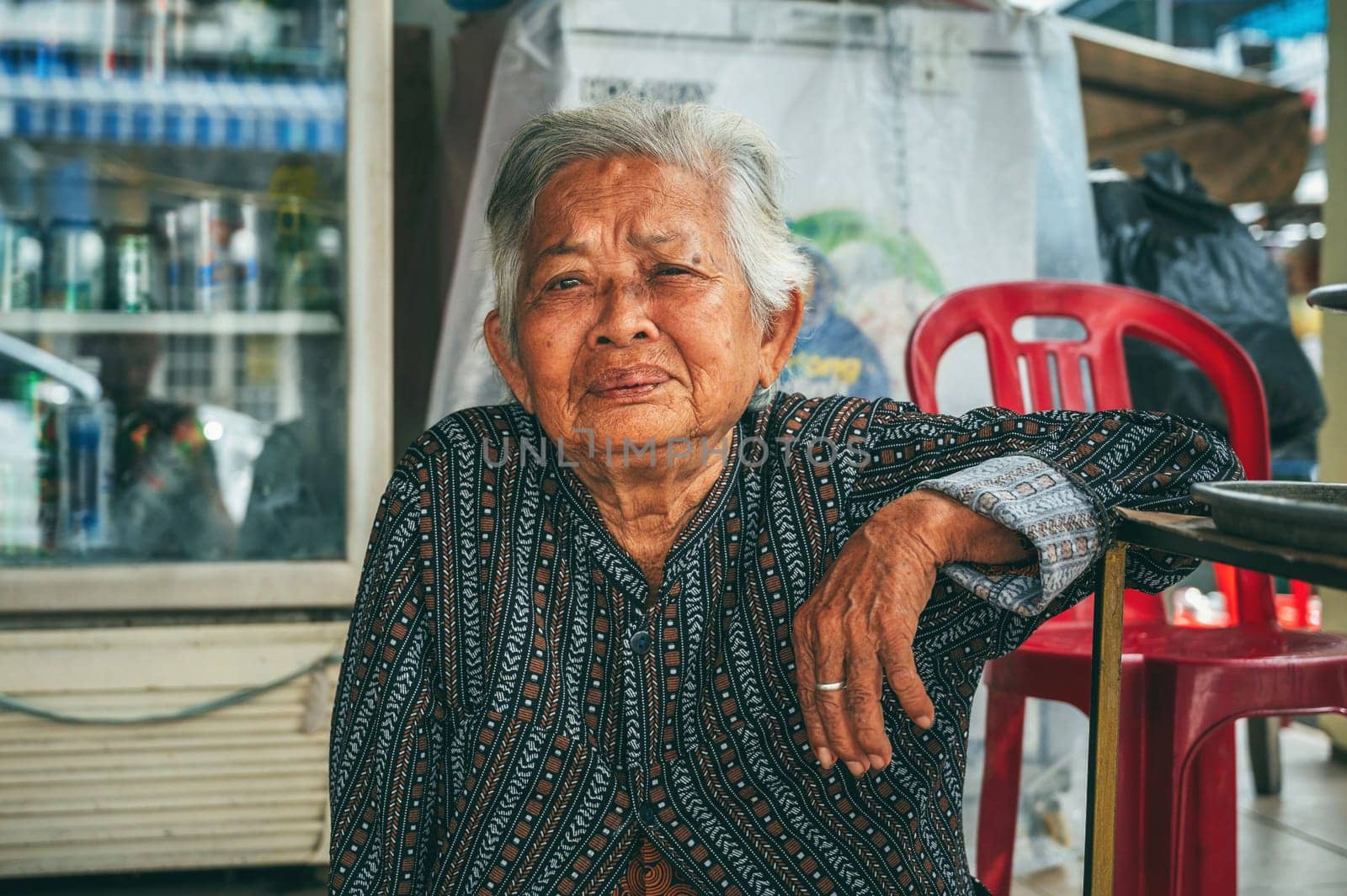Portrait of an elderly Asian Vietnamese woman on street in the old town in Hoi An in Vietnam in Asia. Hoi An, Vietnam - December 2, 2024