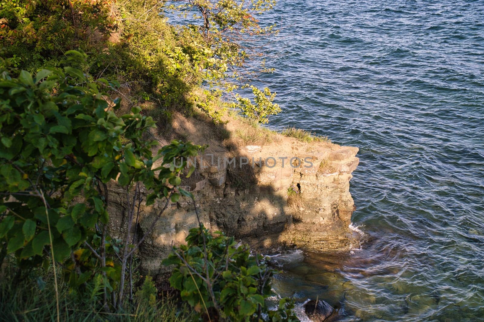 View from a cliff, an island in Sweden on a lake with clear water, surrounded by green trees and nature. Gentle waves, peaceful atmosphere - perfect for rest and relaxation.