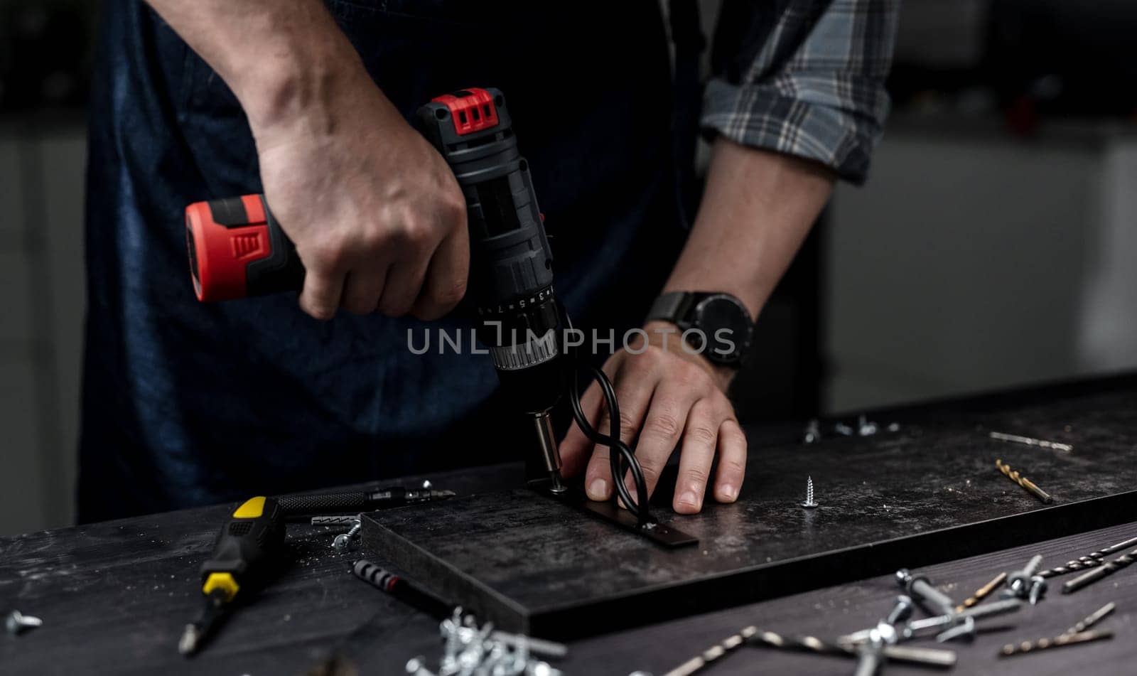 Man Screws Bracket To Shelf With Screwdriver, Hands In Close-Up