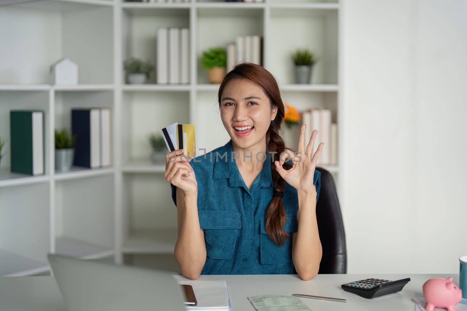 The woman beams with confidence as she showcases her credit cards, representing a successful approach to financial management and savings.