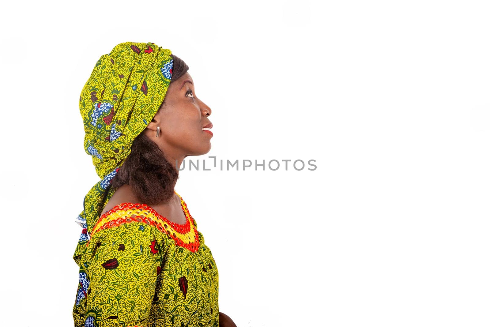 Adult African woman wearing a green loincloth is stopped on one side, with a natural face lifted to the sky and accompanied by a smile