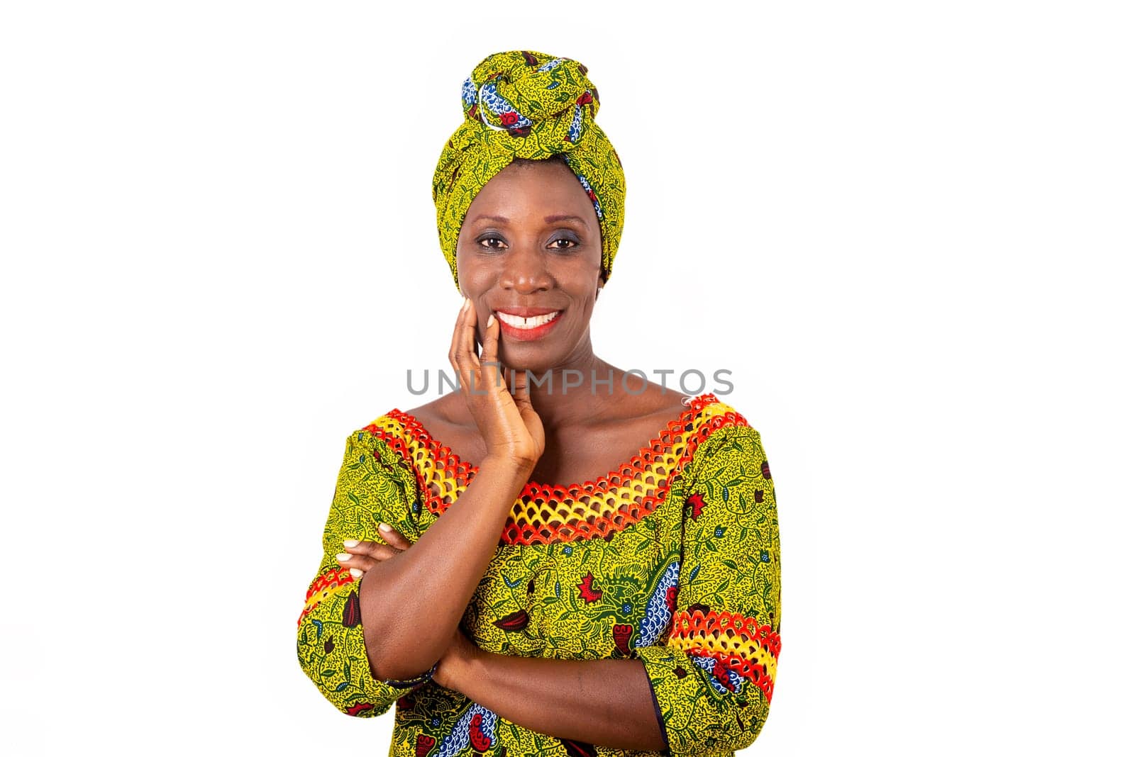 beautiful African adult woman dressed in green loincloth is smiling with arms crossed and hand raised on the cheek