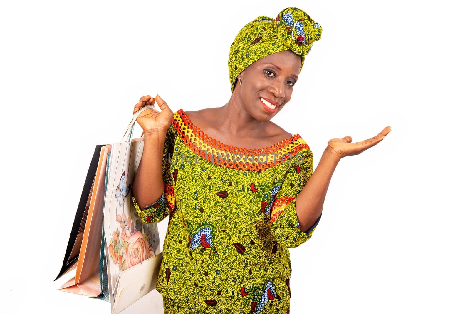 beautiful african adult woman dressed in loincloth and green scarf on the head is happy showing shopping bags while raising hands