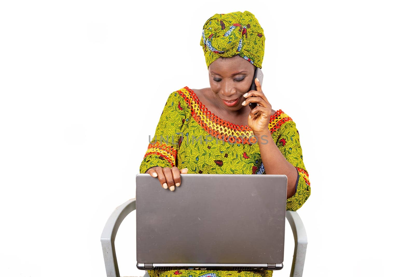 beautiful mature woman sitting in traditional dress on white background communicating and looking at laptop smiling.