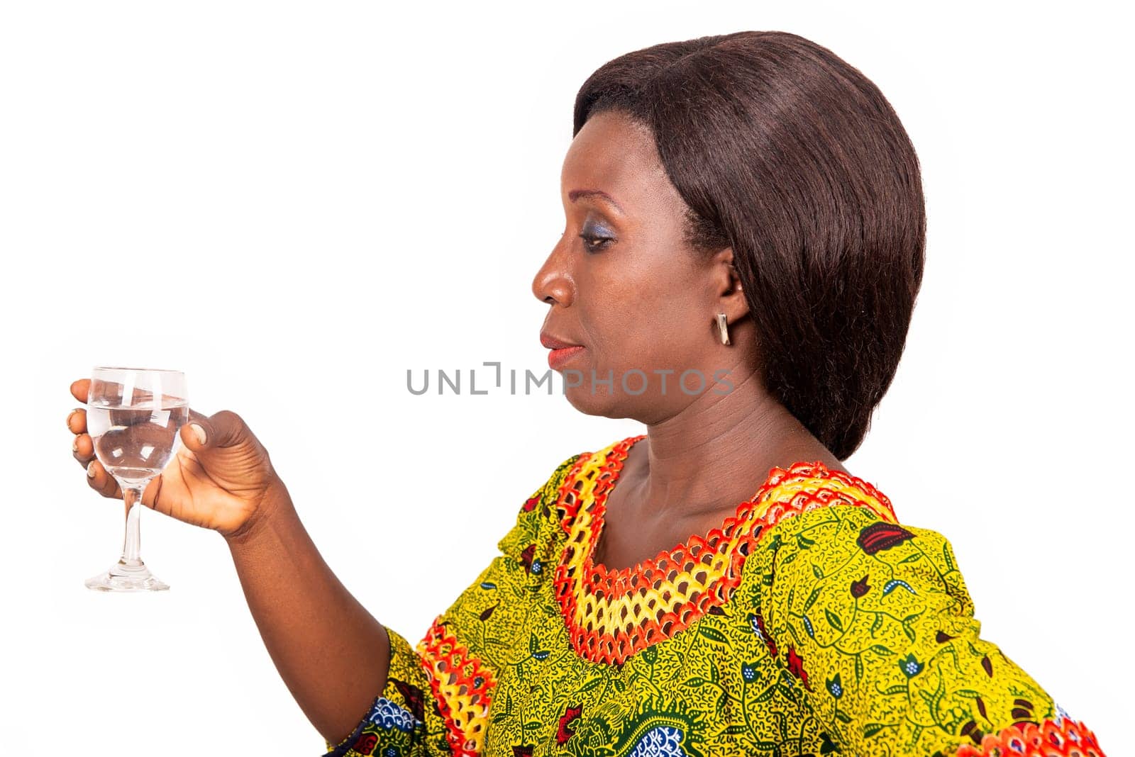 beautiful african adult woman dressed in green loincloth and long black hair holding a glass of clear clean mineral water in hands, healthy drink.