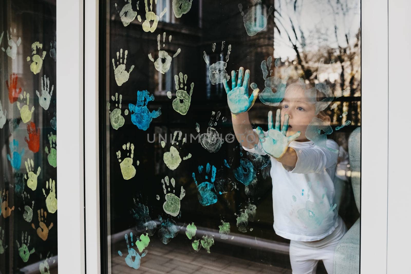 Girl paints with palms on the window. Quarantine Stay at home