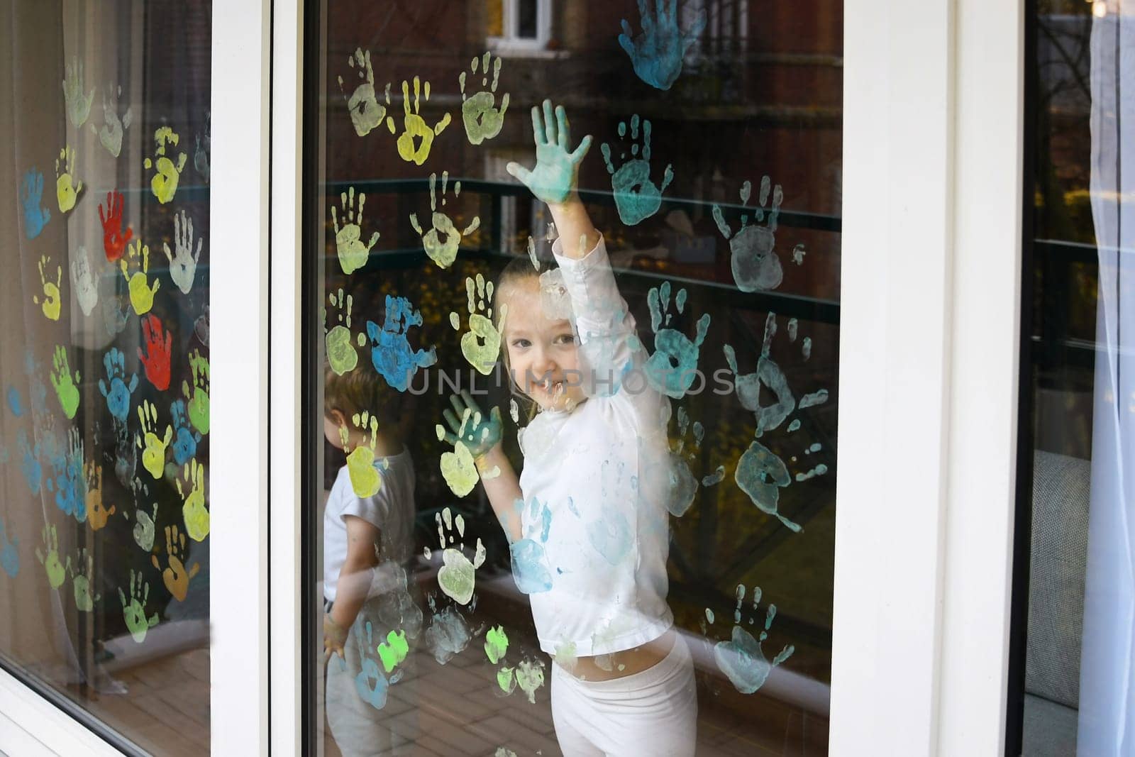 Children paint with palms on the window. Quarantine Stay at home