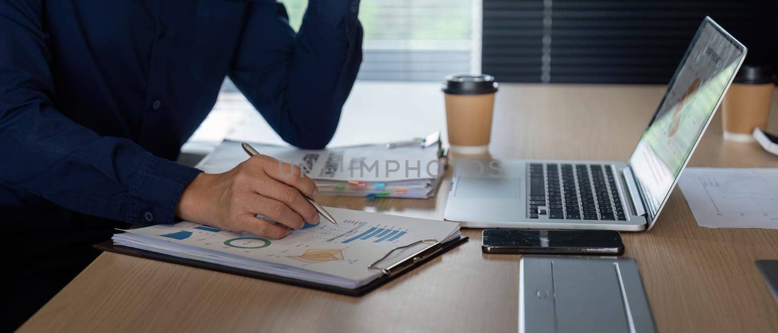 A colleague engages in meticulous note-taking while analyzing financial data in a modern office. The emphasis is on strategic planning and understanding key metrics.