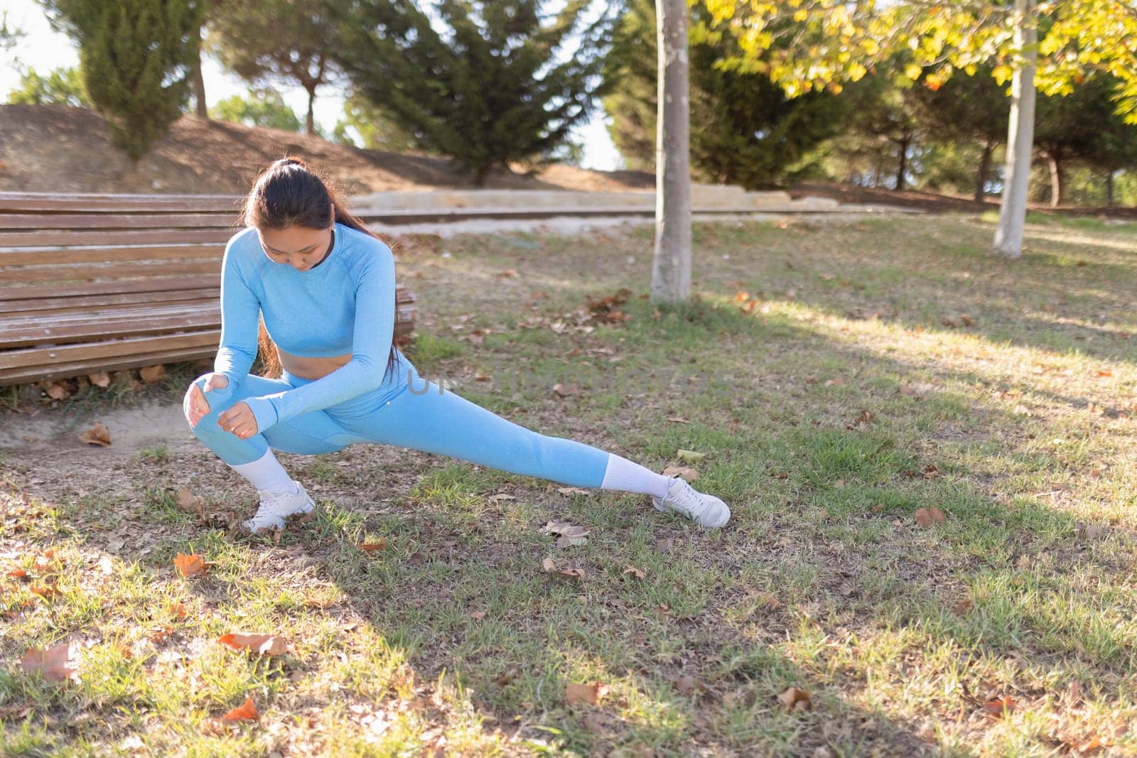 Asian woman wearing sportswear performing leg stretches in a park