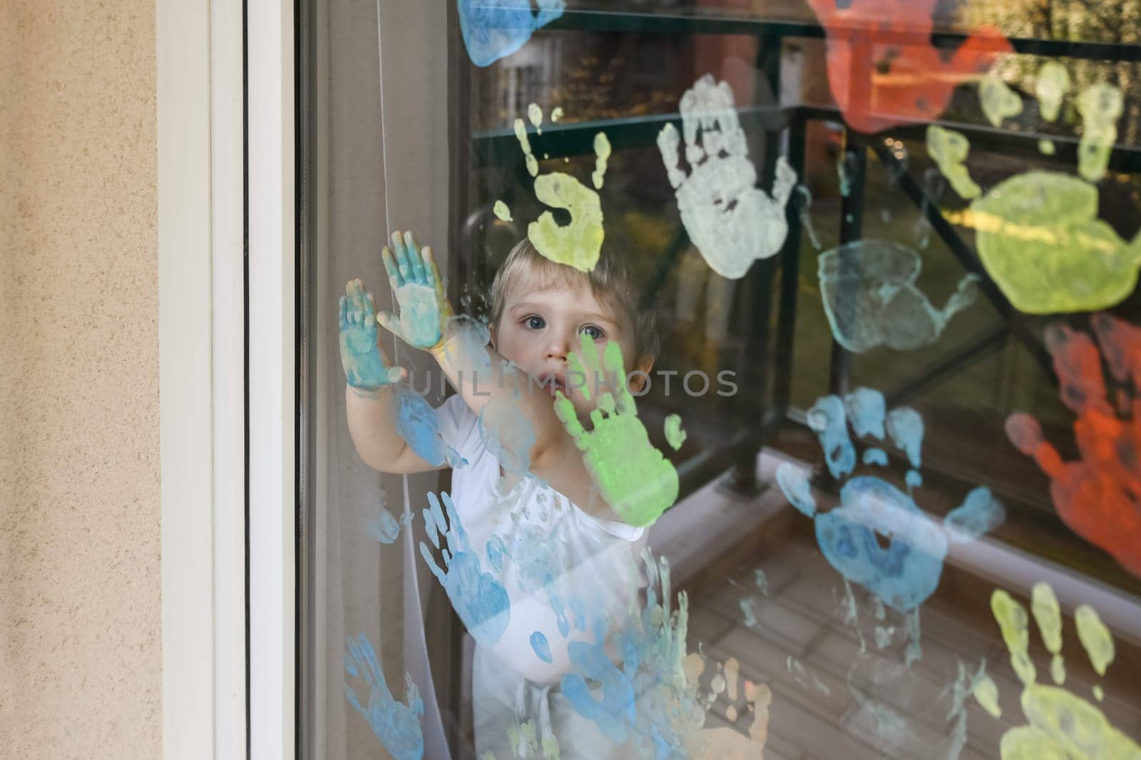 Kid paints with palms on the window. Quarantine Stay at home