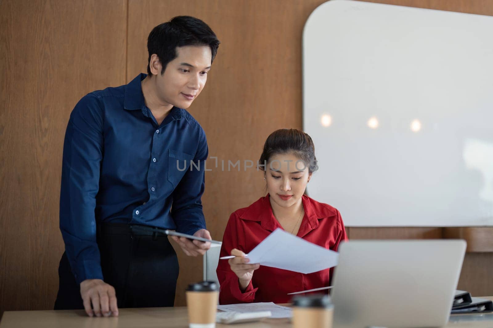 Two colleagues diligently analyze financial documents and charts, discussing important insights during their meeting, emphasizing data-driven decision-making.