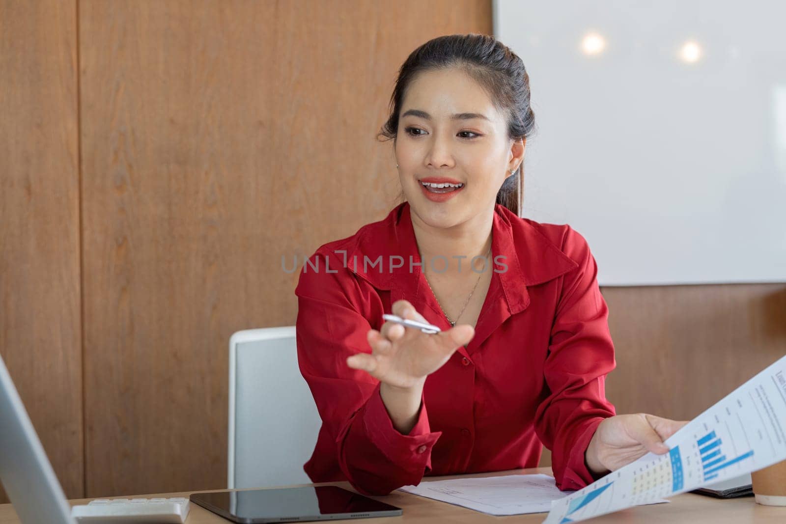 A business professional in a red blazer is discussing financial reports, captivated as she points out important data during a meeting. Perfect for online finance themes.