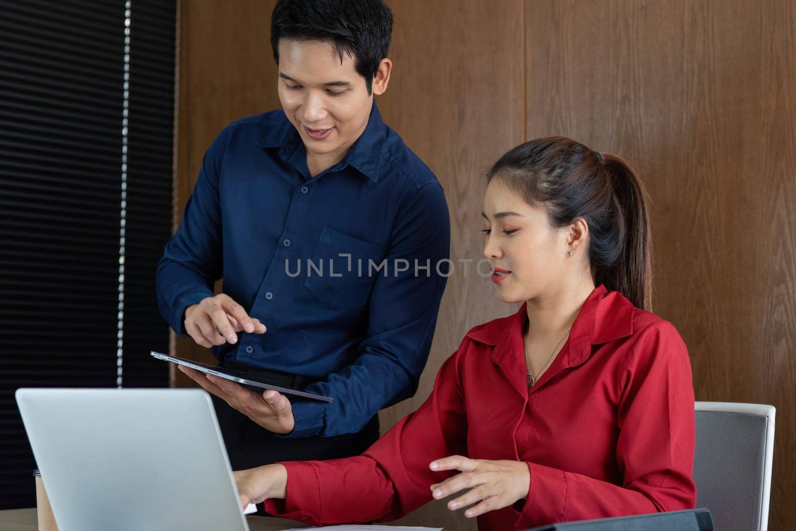 A man and woman engage in a collaborative financial discussion, analyzing reports on a tablet and reviewing data to enhance strategic decisions in business.