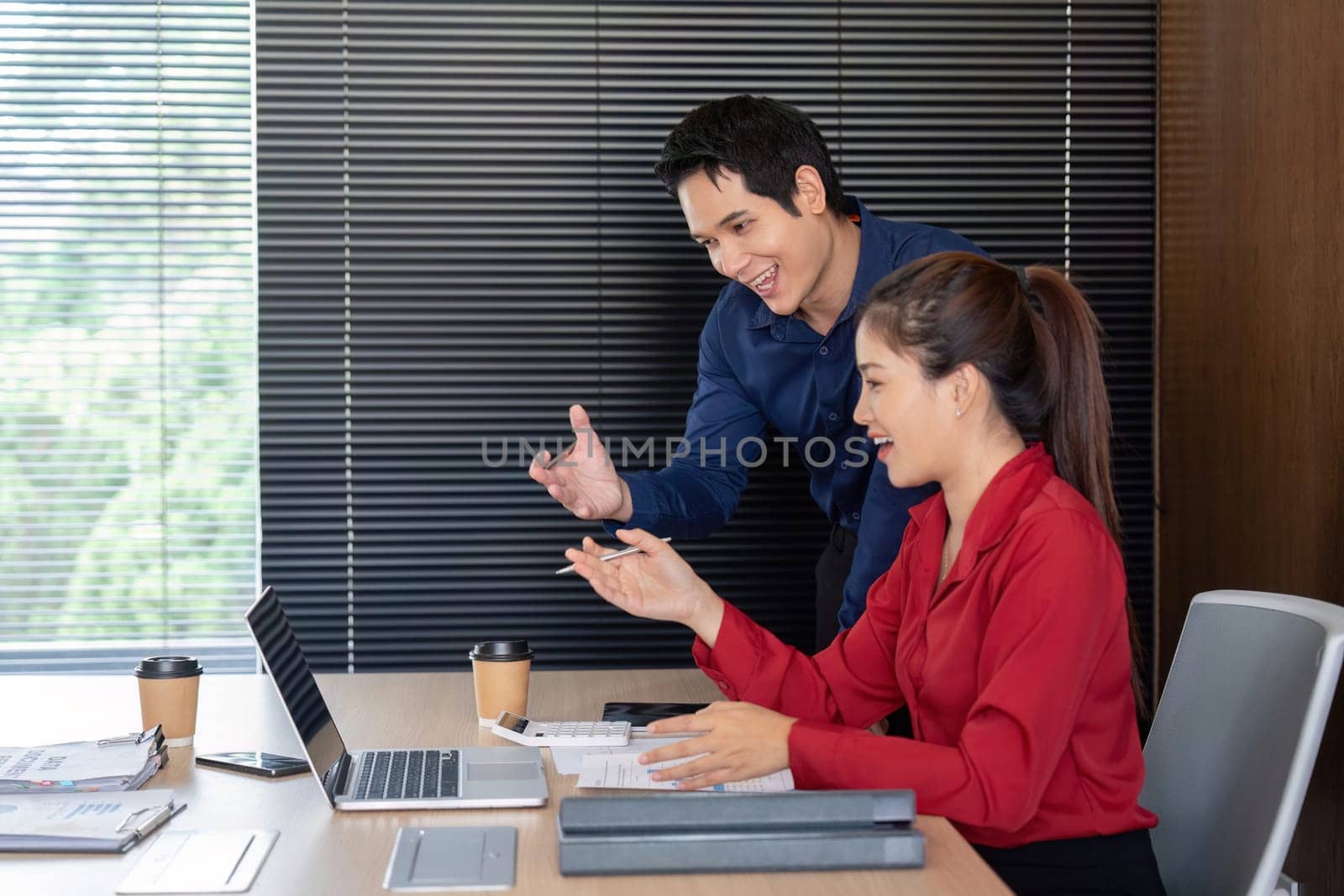 In a modern office, two professionals analyze financial data while brainstorming strategies for business growth.