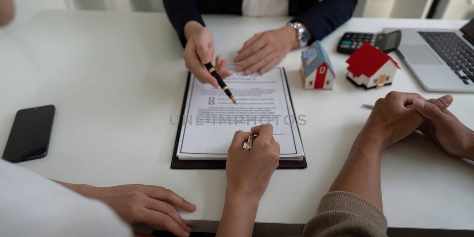 A couple engages with a real estate agent, discussing property details while reviewing and signing contracts in a professional setting focused on home buying.