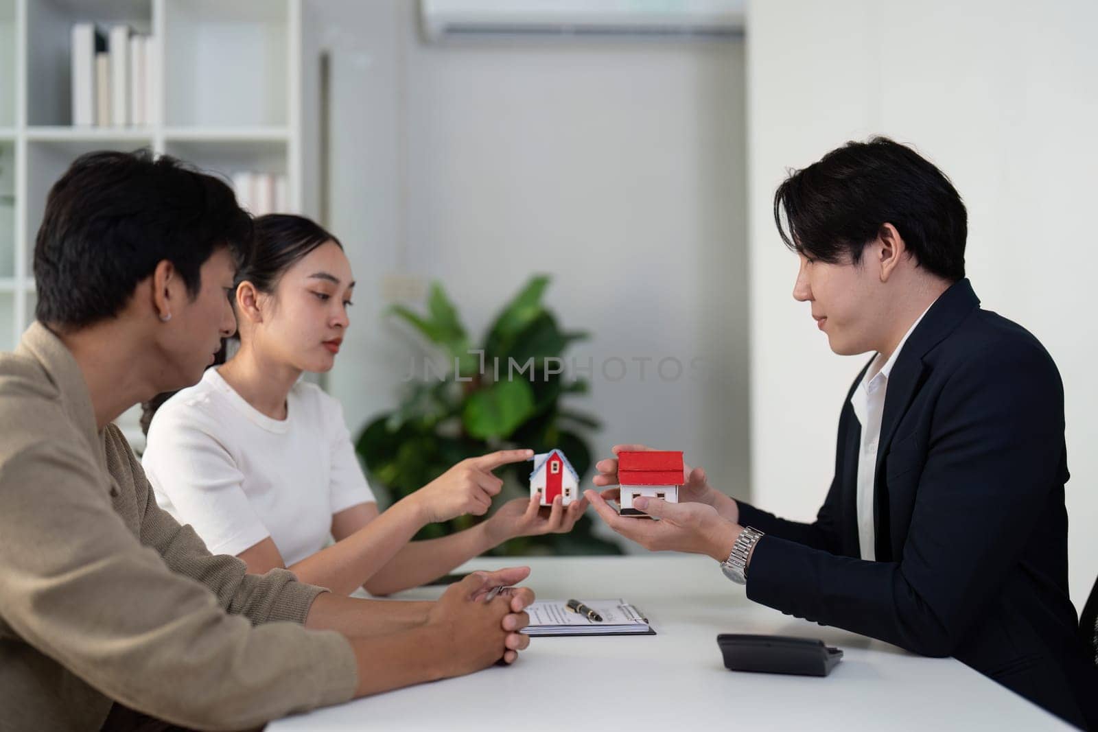 The couple evaluates different properties with their real estate agent, actively discussing features and preferences to find their dream home.