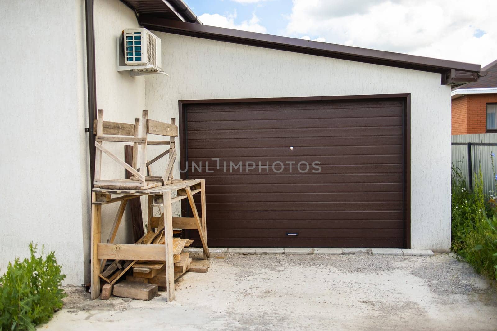 Woodwork and scaffolding in front of brown garage door. Exterior home renovation and tidy, building storage.