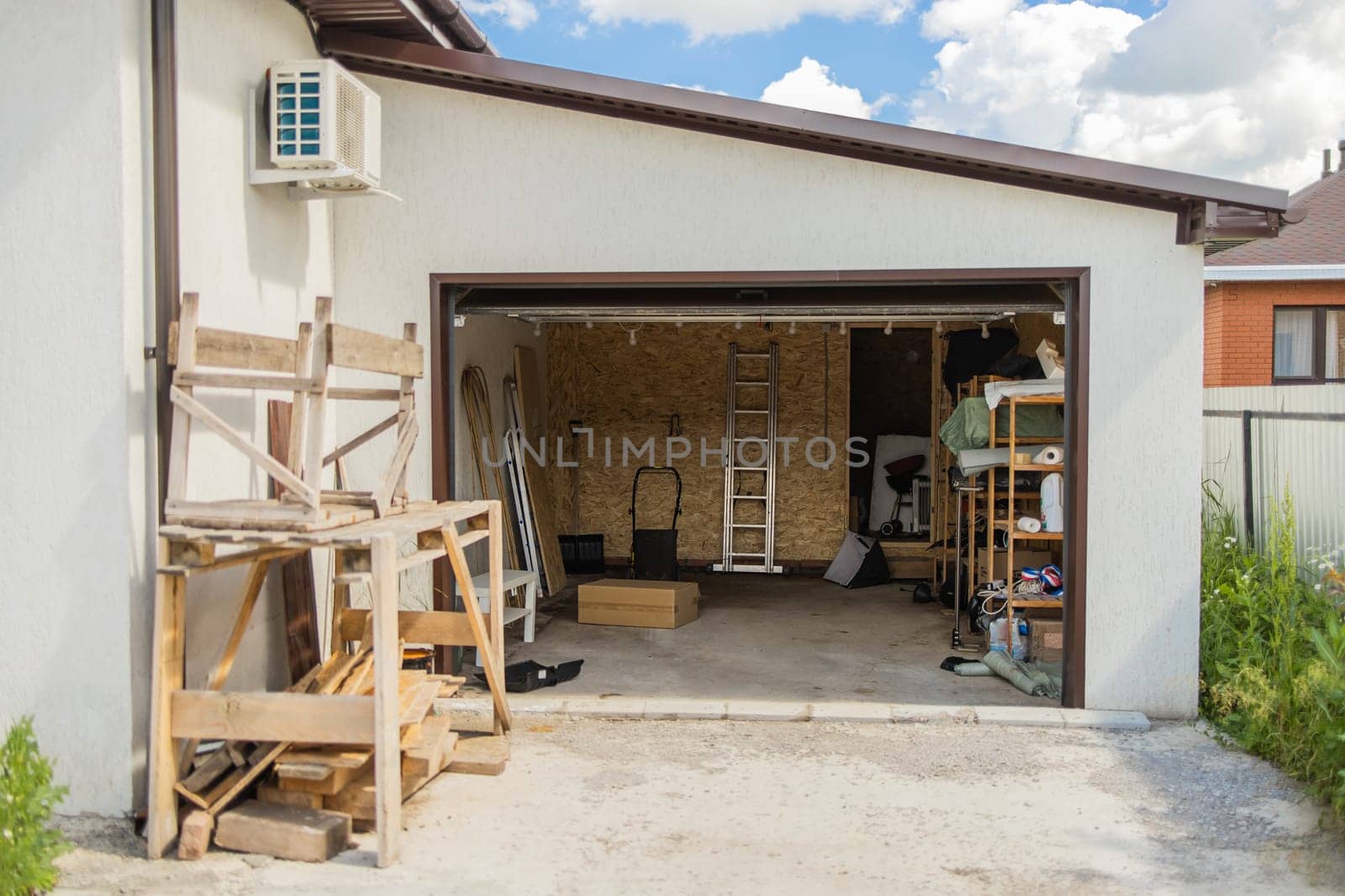 Open garage with tools and wooden planks. Organized storage and efficient use of residential workspace for home maintenance