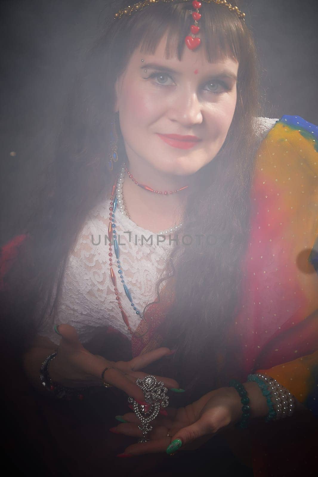 A mature woman poses gracefully in a vibrant sari, displaying intricate jewelry, capturing the essence of Indian fashion and culture.