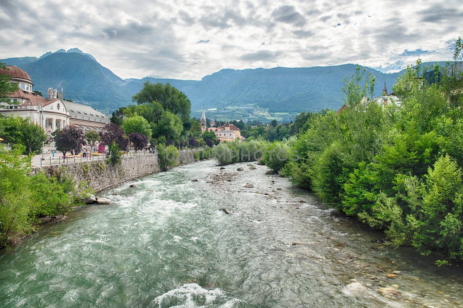 The Passirio River is flowing through the city center of Merano, a famous spa town in South Tyrol, Italy, surrounded by mountains