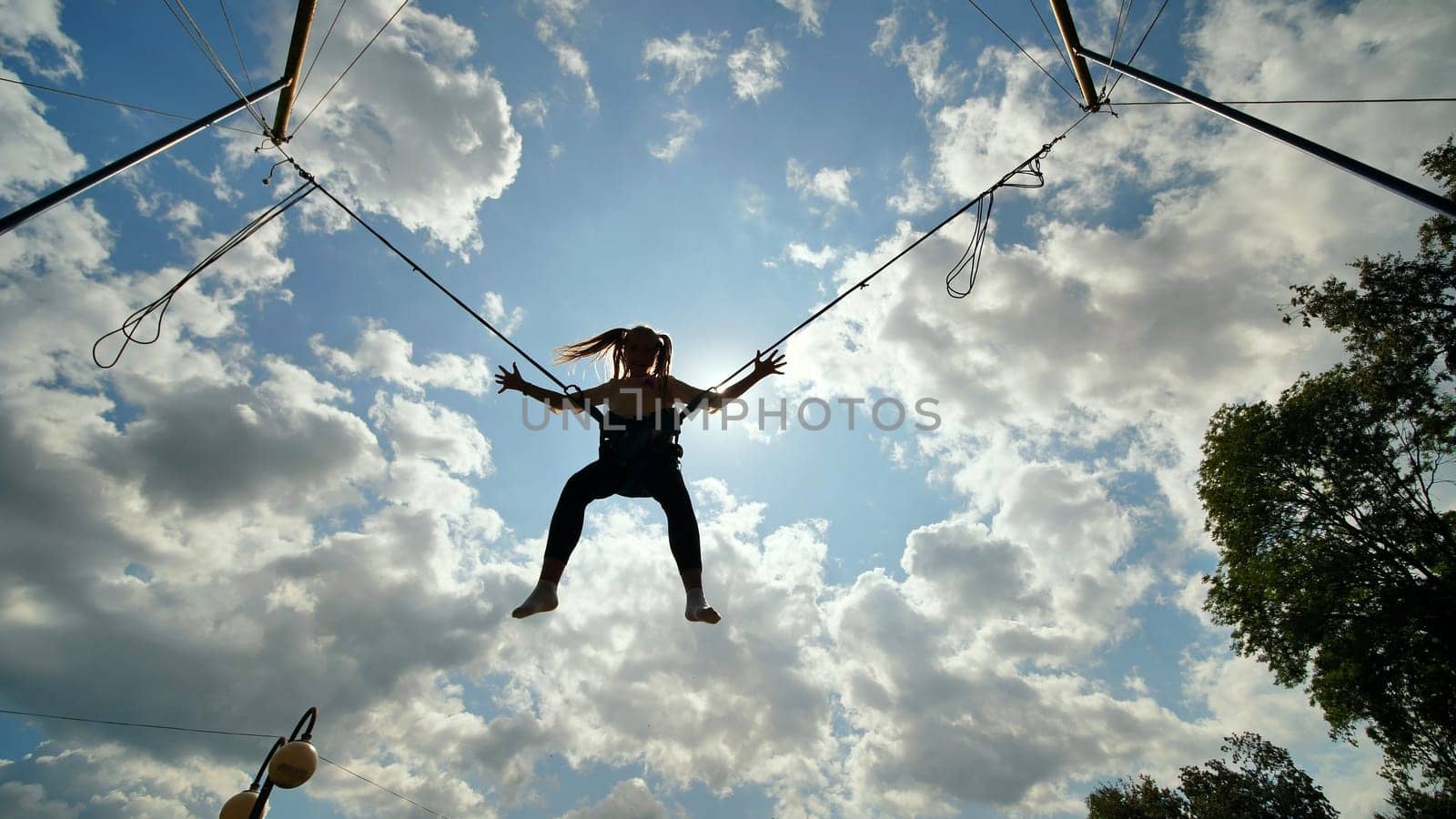 Teenage girl silhouette jumping on the trampoline bungee jumping