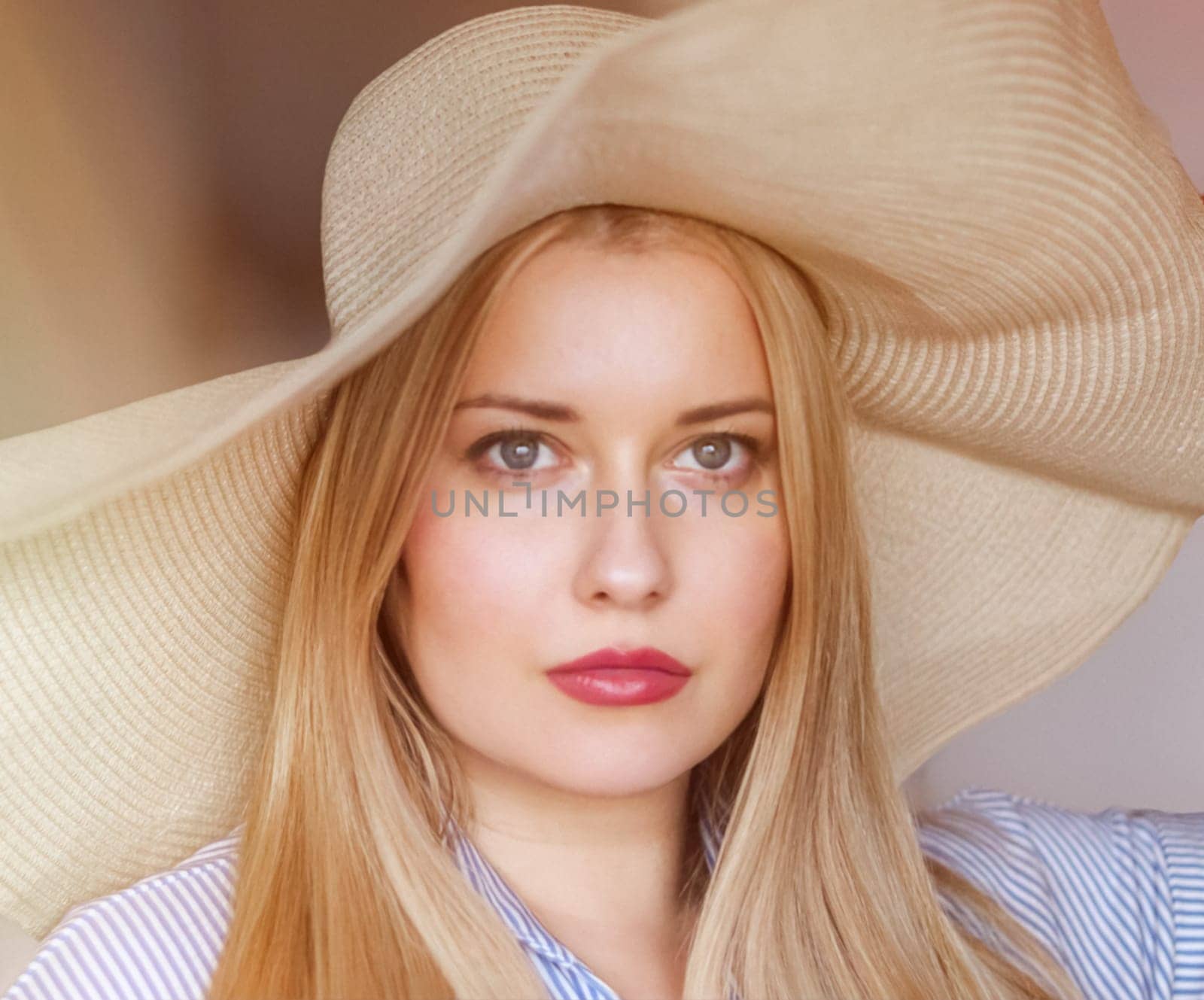 Woman, fashion and summer country charm, blonde beauty and elegance in wide brimmed beach hat. Feminine allure, timeless style and graceful glow. Smile, straw hat and blue striped blouse, natural lighting and effortless charm, fashion look idea