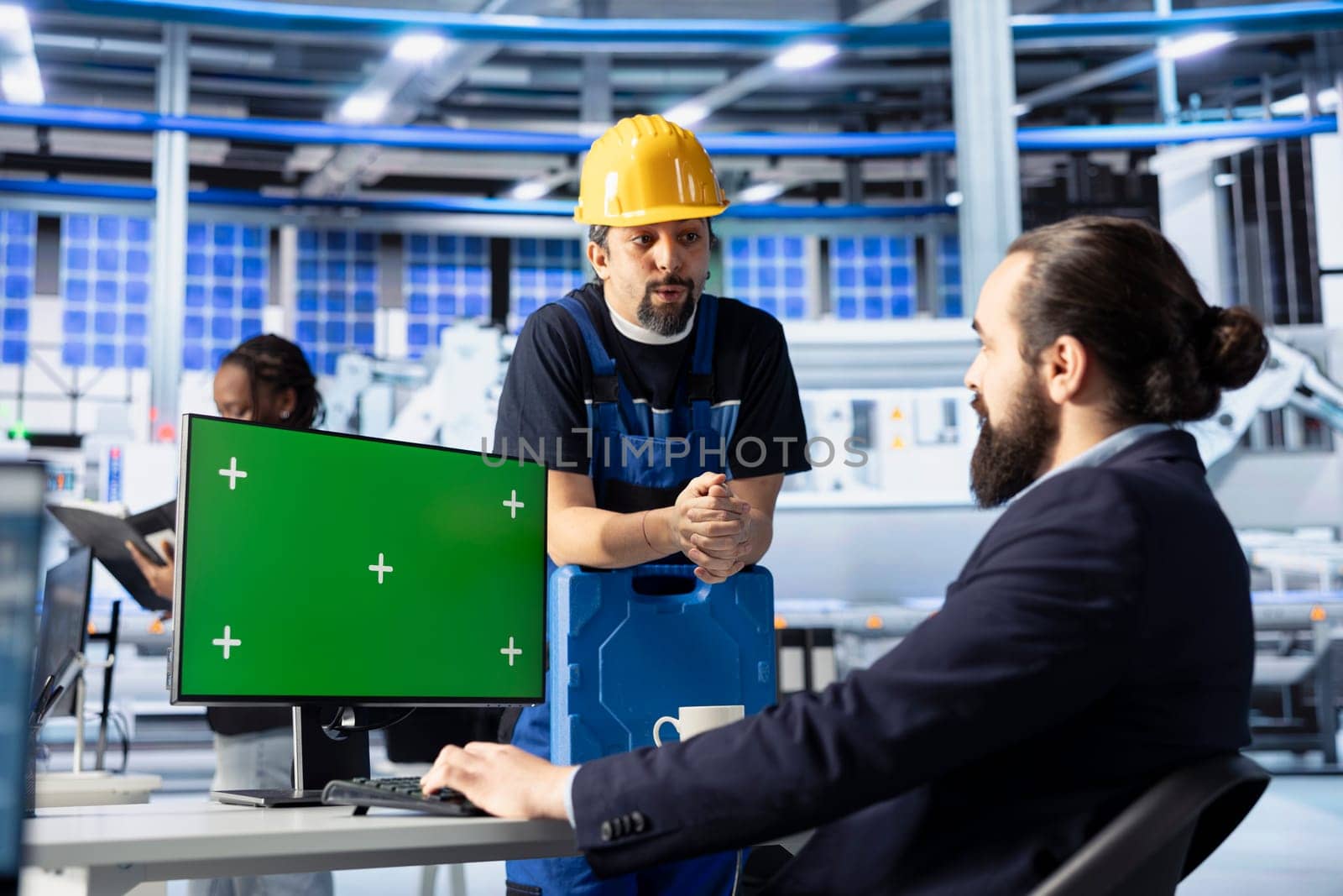 Photovoltaics factory manager using green screen PC to show worker how to optimize production flow. Sustainable energy solar panels plant supervisor monitors manufacturing process on mockup computer
