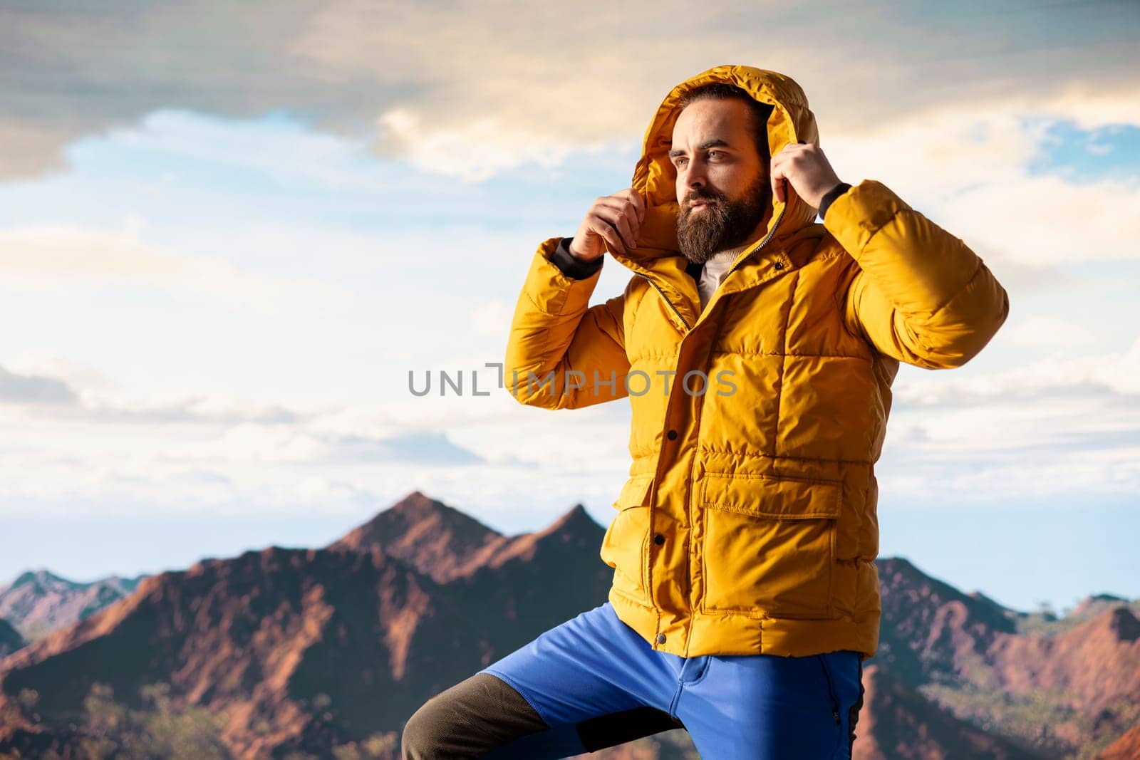 Hiker traveler pauses to admire the panoramic mountain scenery on the hill top, endless sky and rocky peaks creating a breathtaking backdrop for mental clarity. Adventure seeker outdoors.